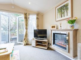 A living room with a television and fireplace at Sprindrift - Kelling Heath Holiday Park, Holt