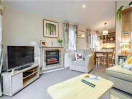 A living room with a television and a fireplace at Sprindrift - Kelling Heath Holiday Park, Holt
