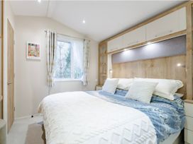 A bedroom with a bed, window and shelving at Sprindrift - Kelling Heath Holiday Park in Holt