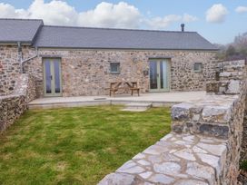 An outdoor area with a stone house and a table at Dairy Cottage in Oxwich