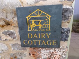 A sign displaying the name Dairy Cottage with a cow illustration at Dairy Cottage in Oxwich