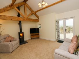 A living room with a television and sofas at Dairy Cottage in Oxwich