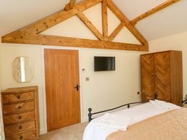 A bedroom with a bed, wardrobe, chest of drawers, and television at Dairy Cottage in Oxwich