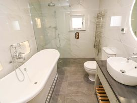 A bathroom with a bathtub, shower, and sink at Dairy Cottage in Oxwich