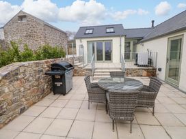 An outdoor area with a table and chairs beside a grill at Dairy Cottage in Oxwich