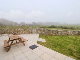 An outdoor patio with a table and benches at Dairy Cottage in Oxwich