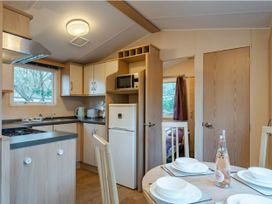 A kitchen with appliances and dining table at Prima -Kelling Heath Holiday Park, Holt