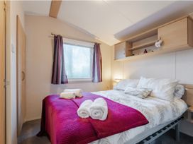 A bedroom with a bed and shelves at Prima -Kelling Heath Holiday Park in Holt