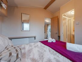 A bedroom with bed, mirror, and adjoining bathroom at Prima -Kelling Heath Holiday Park in Holt
