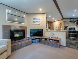 A living room with a television and fireplace at The But n Ben - Kelling Heath Holiday Park in Holt