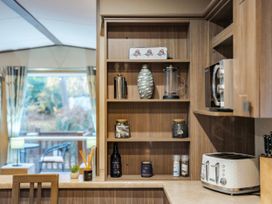 A kitchen with shelves containing various kitchen items at The But n Ben - Kelling Heath Holiday Park in Holt