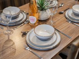 A dining table set with plates, glasses, and a bottle of wine at The But n Ben - Kelling Heath Holiday Park, Holt