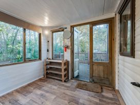 A conservatory with wooden shelves and windows at The But n Ben - Kelling Heath Holiday Park, Holt