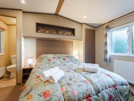 A bedroom with a bed and a bathroom at The But n Ben - Kelling Heath Holiday Park, Holt