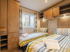 A bedroom with two beds and a window at The But n Ben - Kelling Heath Holiday Park in Holt
