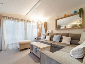 A living room with a sofa and table at Rawsons Retreat - Kelling Heath Holiday Park Holt