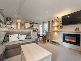 A living room with a sofa and dining table at Rawsons Retreat - Kelling Heath Holiday Park, Holt