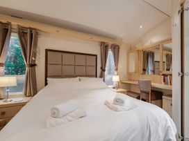 A bedroom with a bed and a dressing table at Rawsons Retreat - Kelling Heath Holiday Park, Holt