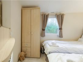 A bedroom with a wardrobe and bed at Rawsons Retreat - Kelling Heath Holiday Park in Holt