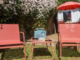 A garden with chairs, a table, a radio and a book at The Arches in Torquay