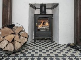 A stove with fire and a wood holder in a living room at Preswylfa