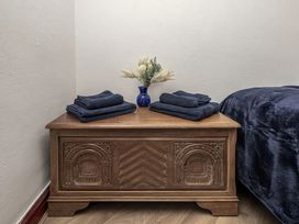 A wooden chest with folded towels and a vase with flowers in a bedroom at Preswylfa