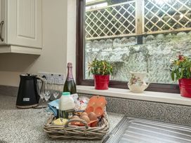 A kitchen counter with a kettle and basket of food items at Preswylfa