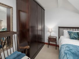 A bedroom with a wardrobe, bed, table and lamp at Preswylfa