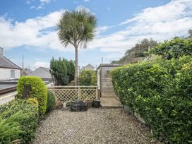A garden with a palm tree and gravel path at Preswylfa