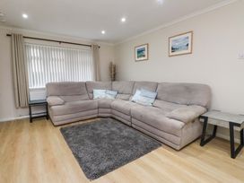 A living room with a sofa and rug at Y Byngalo in Trearddur Bay