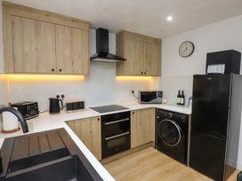 A kitchen with cabinets and appliances at Y Byngalo in Trearddur Bay