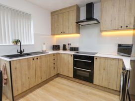 A kitchen with cabinets and appliances at Y Byngalo in Trearddur Bay