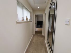 A hallway with a mirror and window at Y Byngalo Trearddur Bay