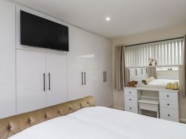 A bedroom with a television and a dressing table at Y Byngalo in Trearddur Bay