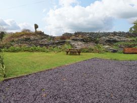 A garden with a picnic table and rocky landscape at Y Byngalo in Trearddur Bay