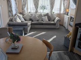 A living room with a sofa and dining table at 104 Lido Beach in Prestatyn