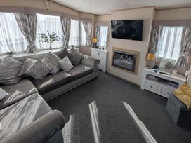 A living room with a sofa and television at 104 Lido Beach in Prestatyn