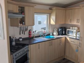A kitchen with cabinets, stove, sink and appliances at 104 Lido Beach Prestatyn