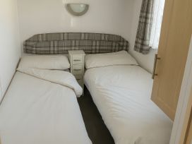 A bedroom with two beds and a nightstand at 104 Lido Beach in Prestatyn