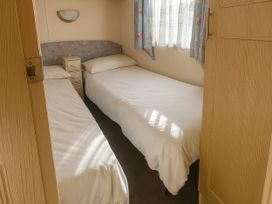 A bedroom with two single beds and a nightstand at 104 Lido Beach in Prestatyn