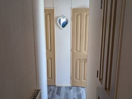 A hallway with doors and a mirror at 104 Lido Beach in Prestatyn