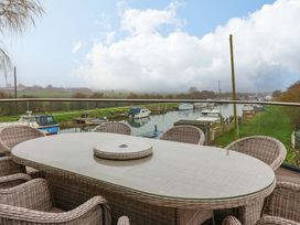 An outdoor dining area overlooking water and boats at Swing Bridge Cottage