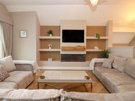 A living room with a sofa and television at Swing Bridge Cottage