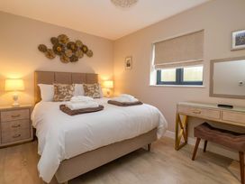 A bedroom with a bed, lamps, and a dresser at Swing Bridge Cottage 