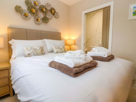 A bedroom with a bed, side table, and towels at Swing Bridge Cottage