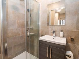 A bathroom with shower, sink, and mirror at Swing Bridge Cottage