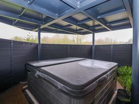 A hot tub under a roof structure in an outdoor area at Swing Bridge Cottage