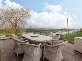 An outdoor dining area with a table and chairs overlooking a river at Swing Bridge Cottage in 