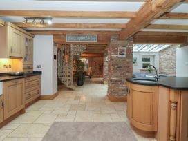 A kitchen with a spiral staircase and wooden cabinets at Mill Race Cottage in Driffield