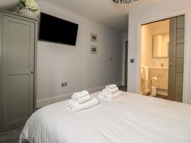 A bedroom with a bed and a bathroom entrance at Mill Race Cottage in Driffield